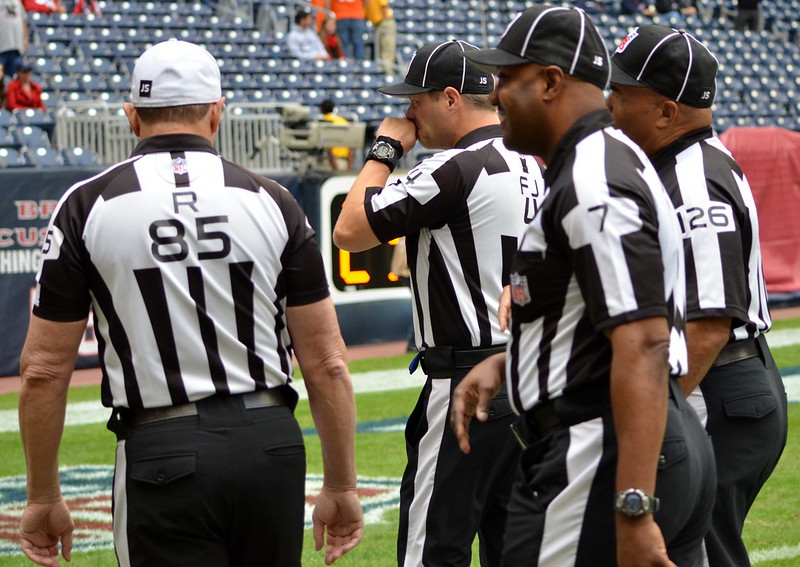 National Football League officials on the field conversing among themselves  