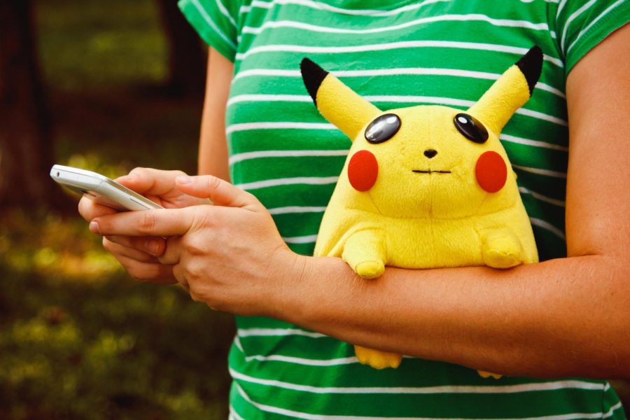 Person using a phone and holding a stuffed plush Pikachu Victory Park in Poltava, Ukraine. 