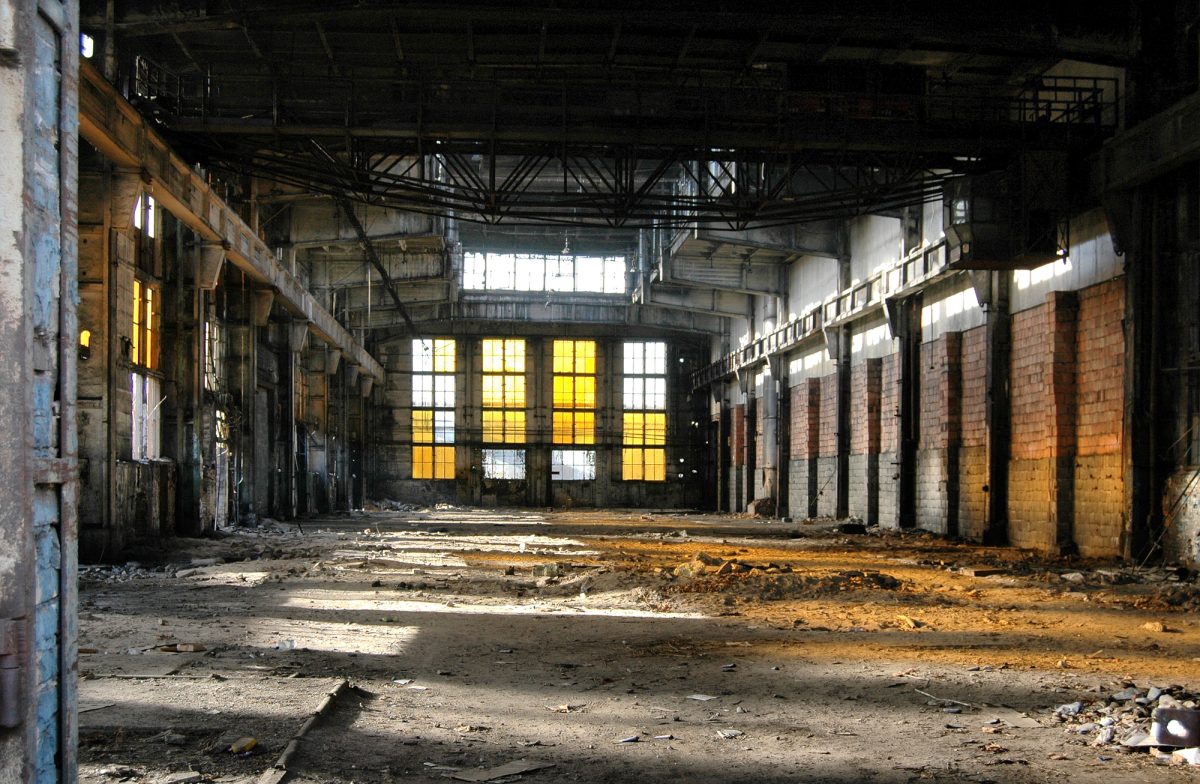An abandoned dilapidated factory floor showing years of disuse and neglect.