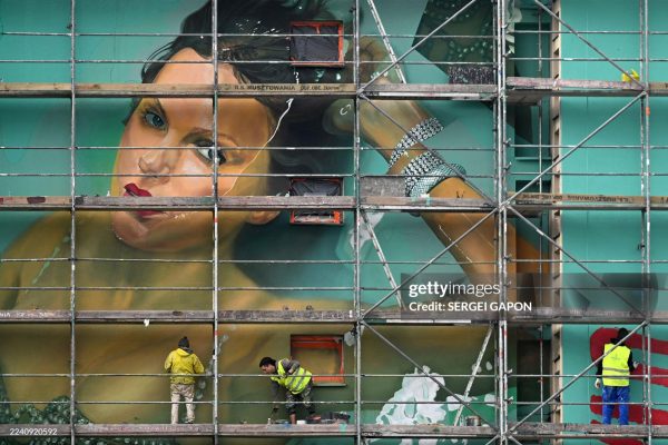 Workers stand on scaffolding to paint a mural advertising US singer Taylor Swift's new album 'The Life of a Showgirl' on the wall of a residential building in Warsaw on October 16, 2025. Taylor Swift has set several streaming records with "The Life of a Showgirl," her new album of bouncy pop songs about love, sex, success -- and score-settling -- that had fans analyzing every word. (Photo by Sergei GAPON / AFP) (Photo by SERGEI GAPON/AFP via Getty Images)