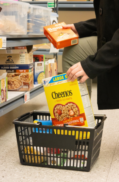 Person putting Cheerios in shopping basket.